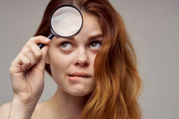 Red-haired woman magnifier near the face hygiene close-up — Stock Photo, Image