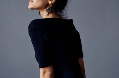 Güzel bir kadın, siyah elbiseli bir hayat stüdyosunda takı takıyor.