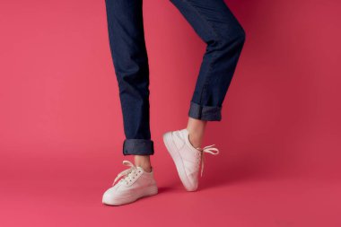 Beyaz spor ayakkabılı kadın bacakları pembe arka plan pozu