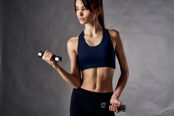 Atletische vrouw fitness oefening halters in de handen van sterke studio gym — Stockfoto