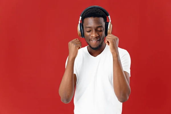 Uomo dall'aspetto africano in t-shirt bianca con cuffie che ascoltano musica divertente — Foto Stock