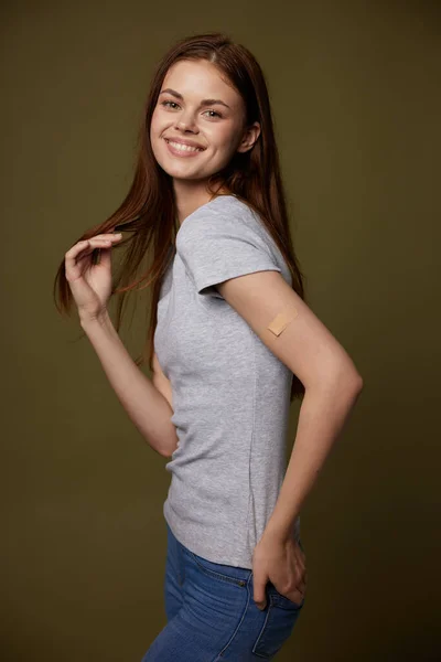 Glad kvinna med självhäftande plåster på handen covid-19 vaccination pass studio — Stockfoto