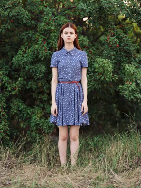 Mavi elbiseli kadın yeşil yapraklı doğa pozu