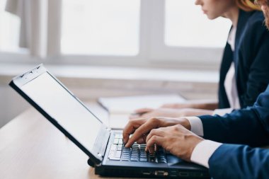 Yöneticiler dizüstü bilgisayarlı iletişim yetkilileriyle bir masada oturuyorlar.