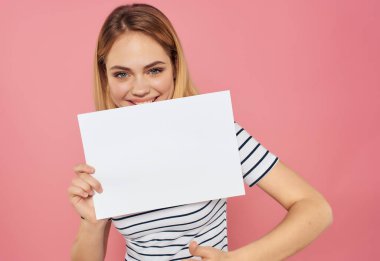 Çizgili tişörtlü, beyaz çarşaflı, el pankartı pembe arka planlı güzel bir kadın.