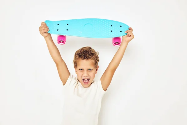 Retrato de niño sonriente monopatín en las manos posando fondo claro —  Fotos de Stock