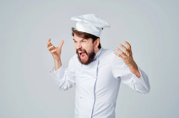 Vousatý muž kuchař uniforma vaření emoce světlo pozadí — Stock fotografie