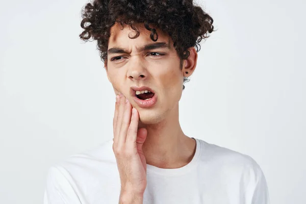 Chlap v bílém tričku s kudrnatými vlasy bolest zubů zdravotní problémy — Stock fotografie