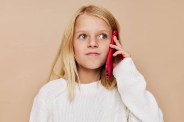 Mutlu şirin kız telefon teknolojisi poz stüdyosunda konuşuyor.