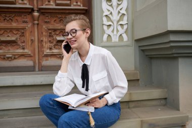 Caddedeki güzel kadın binanın yanında dinleniyor.