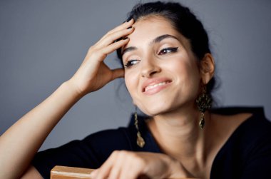 Sandalyenin yanında siyah elbiseli güzel bir kadın. Lüks moda, karanlık arka plan.