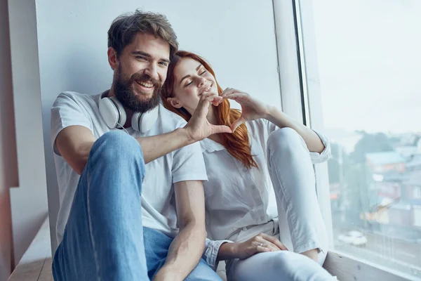 Um jovem casal sentar perto da janela com fones de ouvido romance alegria — Fotografia de Stock