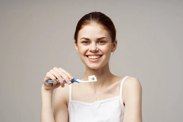Arka Planda Diş Fırçası Olan Beyaz Tişörtlü Neşeli Bir Kadın — Stok fotoğraf