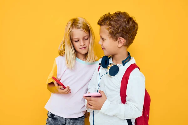 Scuola bambini telefono selfie smorfia divertimento giallo sfondo — Foto Stock