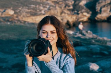 Doğada kamerası olan kadın manzara fotoğrafları çekiyor. 