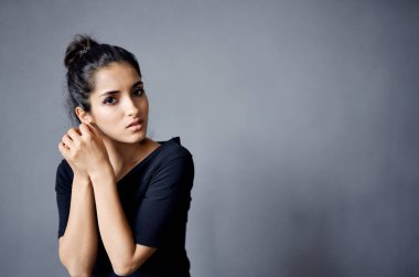 Güzel bir kadın takı takıyor. Siyah elbiseler giyiyor.