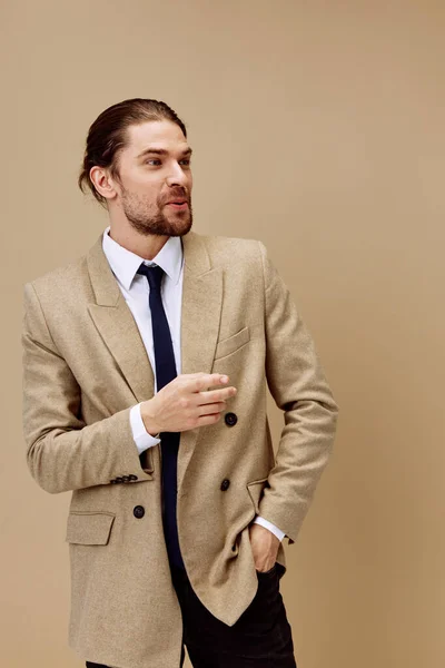 Przystojny mężczyzna w garniturze z krawatem pozowanie beżowy tło — Zdjęcie stockowe