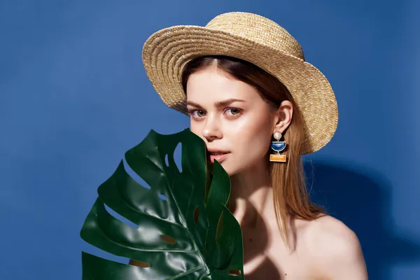 Vacker kvinna grön palm blad poserar blå bakgrund — Stockfoto