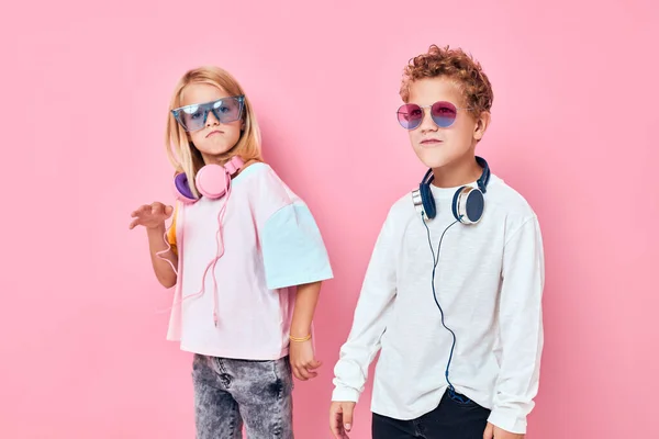 Trendy boy and girl entertainment headphones playing pink color background — Stock Photo, Image