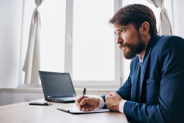 Bir dizüstü bilgisayarın önünde oturan sakallı bir adam.