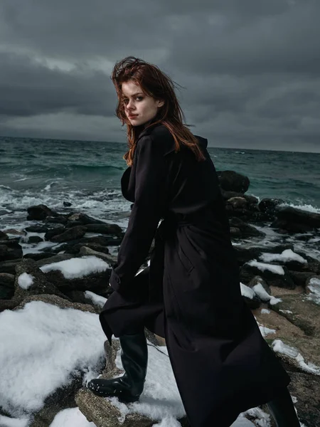 woman in a black coat outdoors landscape ocean dark clouds gothic