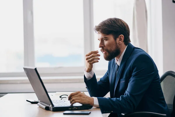 man in a suit in the office in front of a laptop executive manager