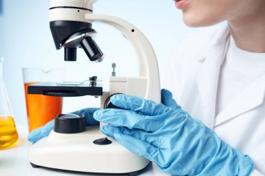 Laboratuvar asistanı mikroskop araştırma stüdyosunda oturuyor.