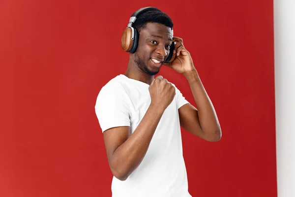 Vrolijke man van Afrikaanse verschijning in koptelefoon muziek rode achtergrond — Stockfoto