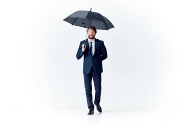 Takım elbiseli bir iş adamı ofis müdürü elinde şemsiyeyle çalışır.
