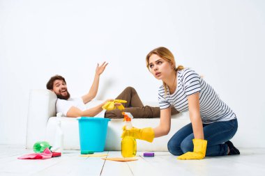 Evli bir çift kanepenin yanında temizlik malzemesi ışık arka planda