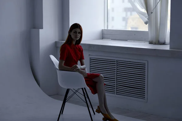 Mulher bonita em vestido vermelho sentado perto da janela — Fotografia de Stock