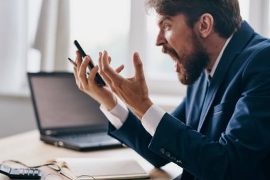 Sakallı adam dizüstü bilgisayarın önünde oturuyor. Stres, öfke uzmanı.