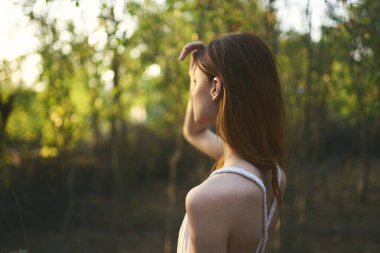 Beyaz elbiseli kadın doğa yürüyüşünde.