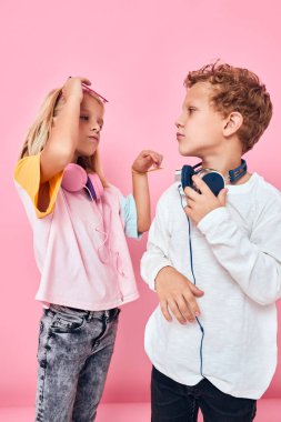 Kulaklıklı komik çocuklar pembe arka planda iletişim kuruyor.