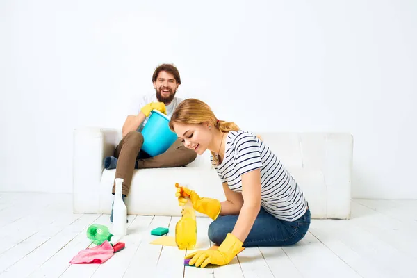 Hombre y mujer cerca del sofá detergente trapos esponjas guantes de protección — Foto de Stock