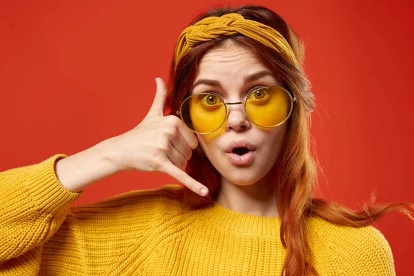 Mulher bonita vestindo óculos amarelos hippie moda fundo vermelho — Fotografia de Stock