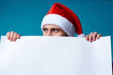 Noel Baba şapkalı yakışıklı adam bayramın mavi arka planını taşıyor.