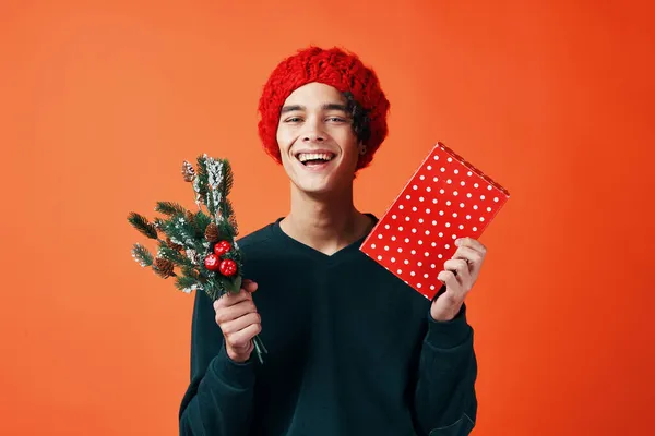 Yeni yıl kıyafetleri içinde bir adam Noel için hediyeler turuncu arka plan — Stok fotoğraf
