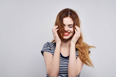 Çizgili tişörtlü güzel bir kadın. Arka planı aydınlık.