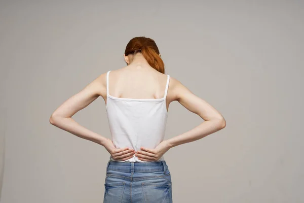 白いTシャツを着た女性腰痛健康問題骨粗しょう症スタジオ治療 — ストック写真