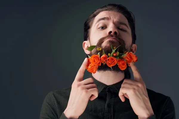 一个英俊的男人,留着胡子摆着花,背景偏僻 — 图库照片