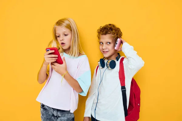 Teenager Jungen und Mädchen verwenden Gadgets mit Kopfhörer gelben Hintergrund — Stockfoto