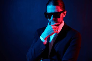 Yakışıklı adam modern tarz takım elbise güneş gözlüğü neon ışık
