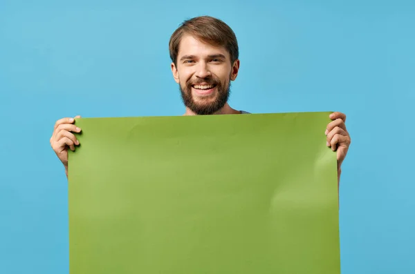 녹색 흉내 내기 포스터를 들고 있는 수염있는 남자의 푸른 배경 할인 — 스톡 사진