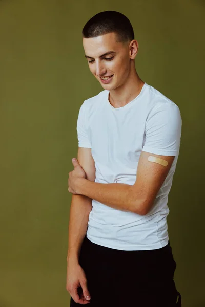 Allegro ragazzo in t-shirt bianca con intonaco adesivo sul passaporto vaccino mano covid-19 sfondo isolato — Foto Stock