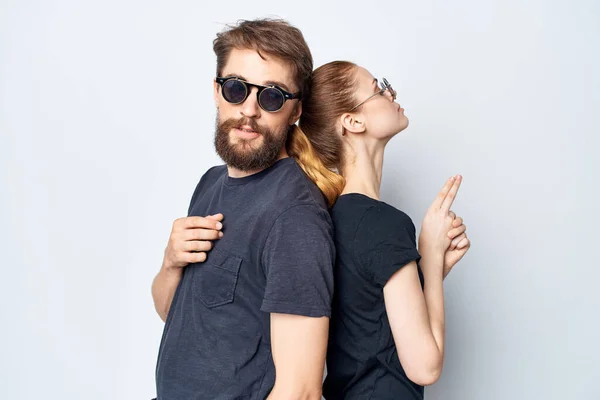 Homem e mulher na moda em preto t-shirt óculos de sol posando fundo leve — Fotografia de Stock
