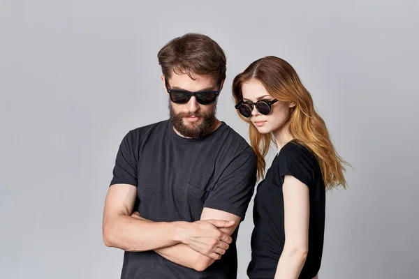 Um jovem casal em preto t-shirt óculos de sol posando isolado fundo — Fotografia de Stock