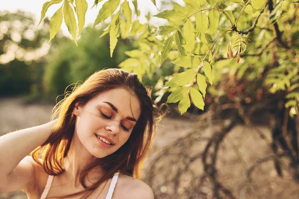 Woman outdoors by tree posing