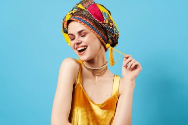 Etnik kökenli neşeli bir kadın. Stüdyoda poz veren çok renkli başörtüsü var.