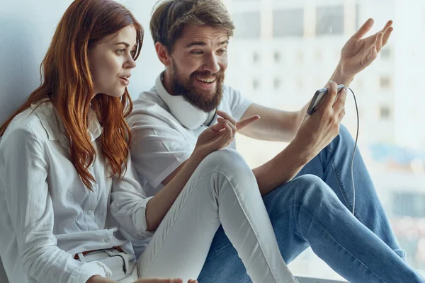 Hombre y mujer se sientan cerca de la ventana con auriculares juntos tecnología apartamentos — Foto de Stock